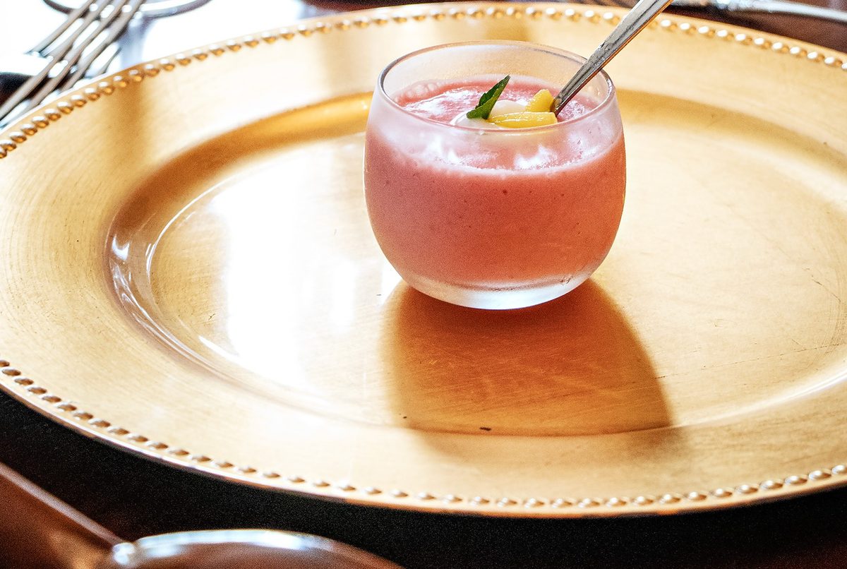 First course — house-made fruit smoothie with mint and citrus garnish on a gold charger plate