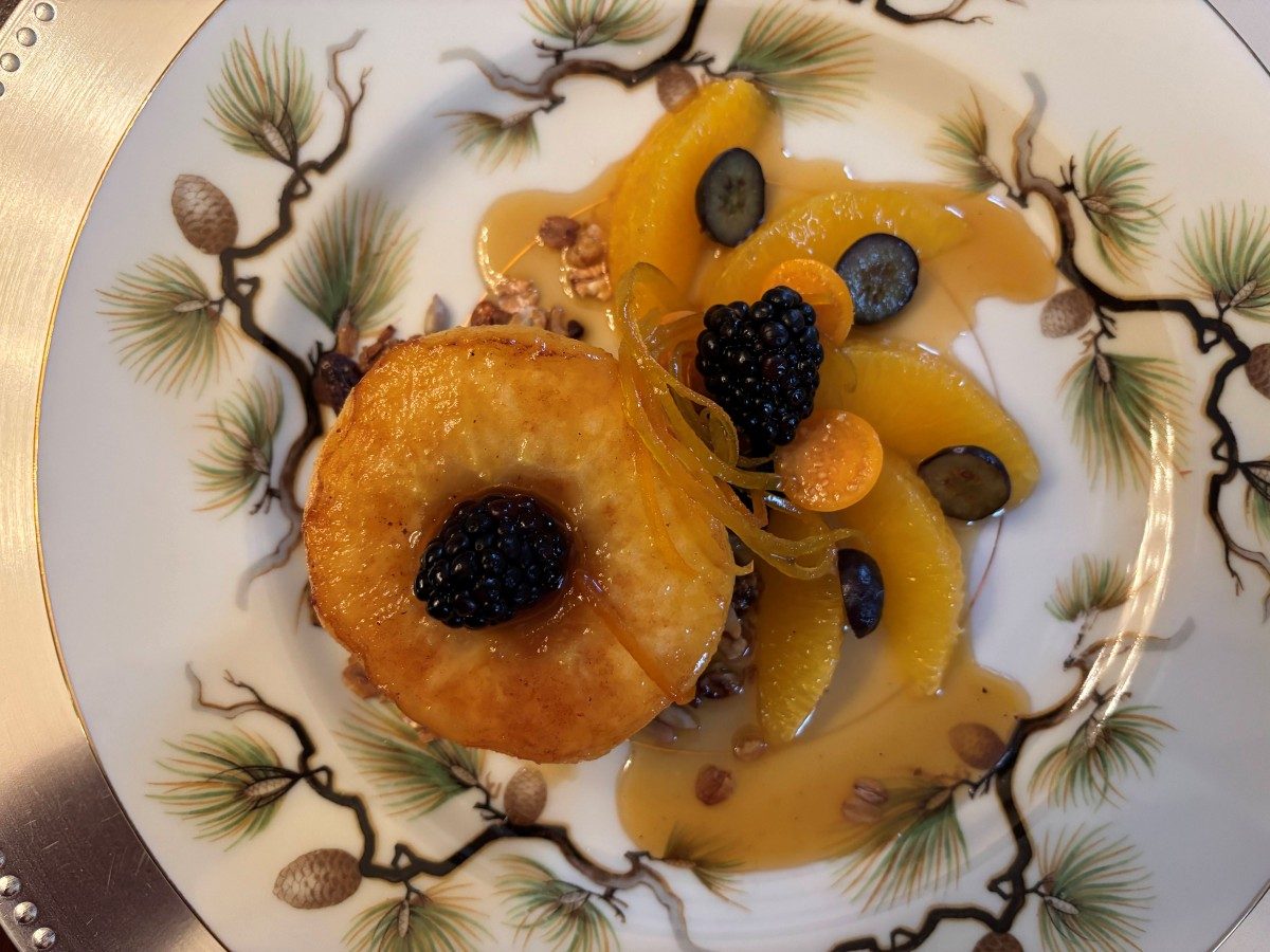 Second course — caramelized apple ring with blackberries, citrus segments, and house-made granola on hand-painted china