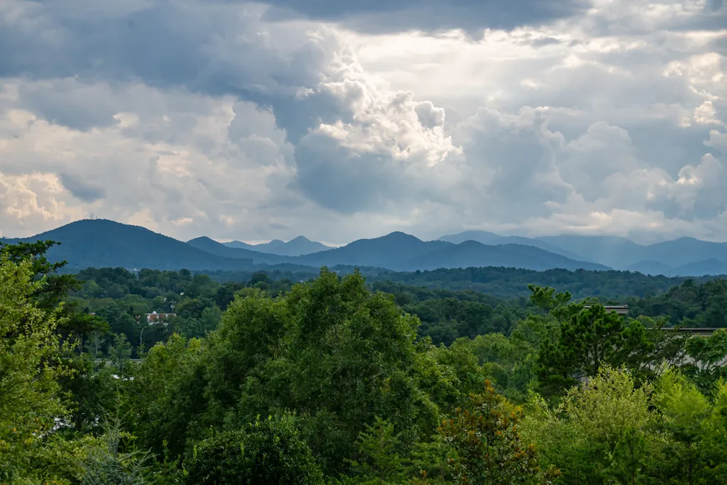 The long view west from the grounds: layered ridges of the Blue Ridge Mountains under a sky of breaking summer clouds.