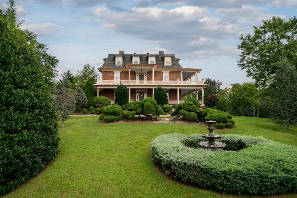 The three-story brick mansion seen from the lower lawn on a bright summer day, with the tiered fountain and clipped boxwood beds in the foreground.