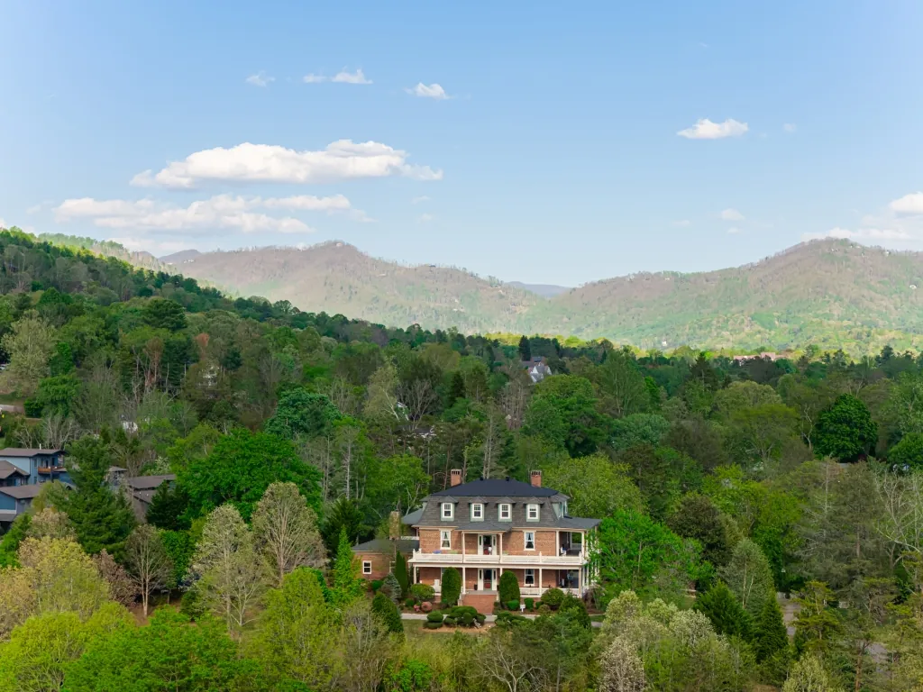 The mansion nestled in spring greenery with the layered ridges of the Blue Ridge Mountains rising on the horizon.