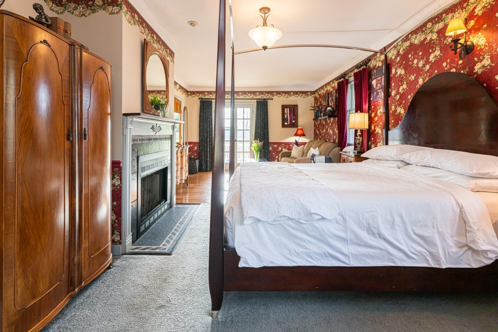 All That Jazz suite — king canopy bed with fireplace and antique armoire at The Reynolds Mansion