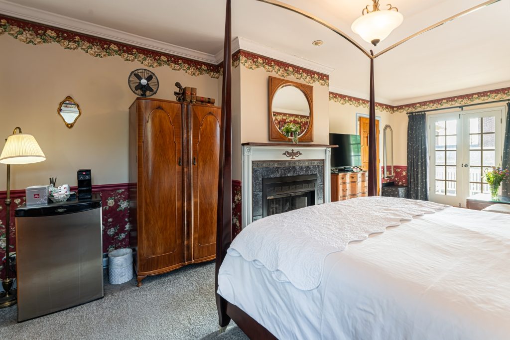 All That Jazz suite — bedroom with mantel mirror and French doors to private balcony at The Reynolds Mansion