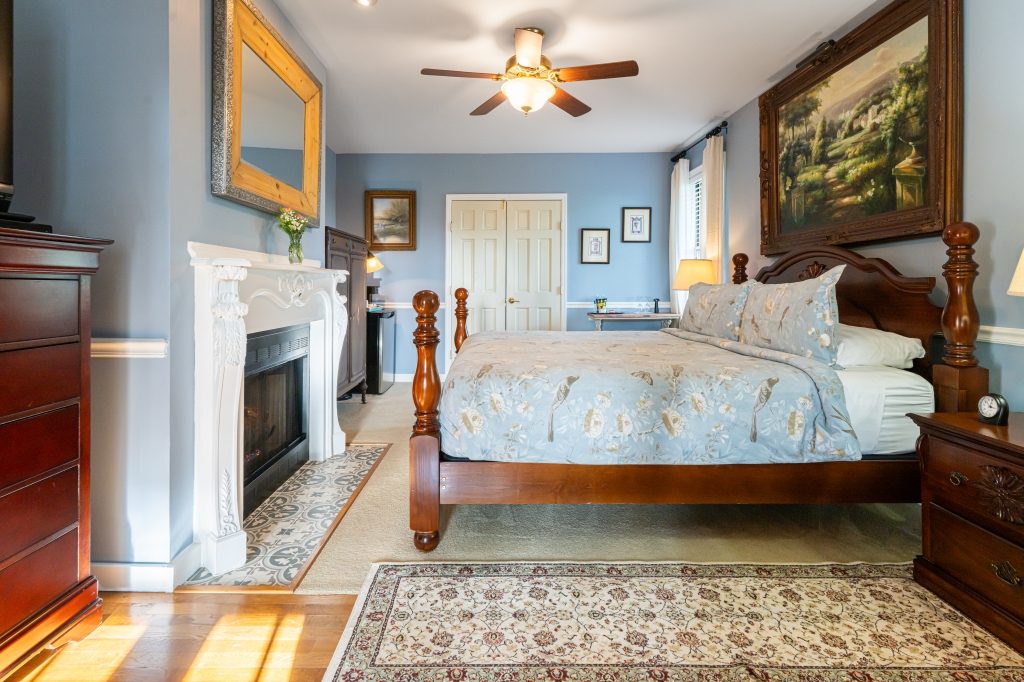 Blue Hydrangea suite — king bed with fireplace and oil painting at The Reynolds Mansion