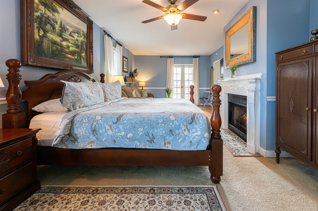 Blue Hydrangea suite — king bed with marble fireplace and antique armoire at The Reynolds Mansion