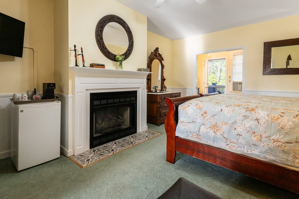 Elephant Walk suite — bedroom with marble fireplace and French doors to deck at The Reynolds Mansion