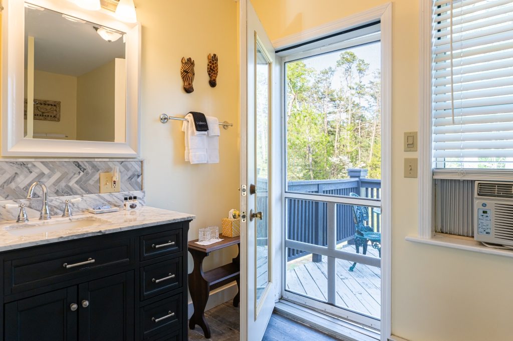 Elephant Walk suite — private bathroom with marble vanity and door to private deck at The Reynolds Mansion
