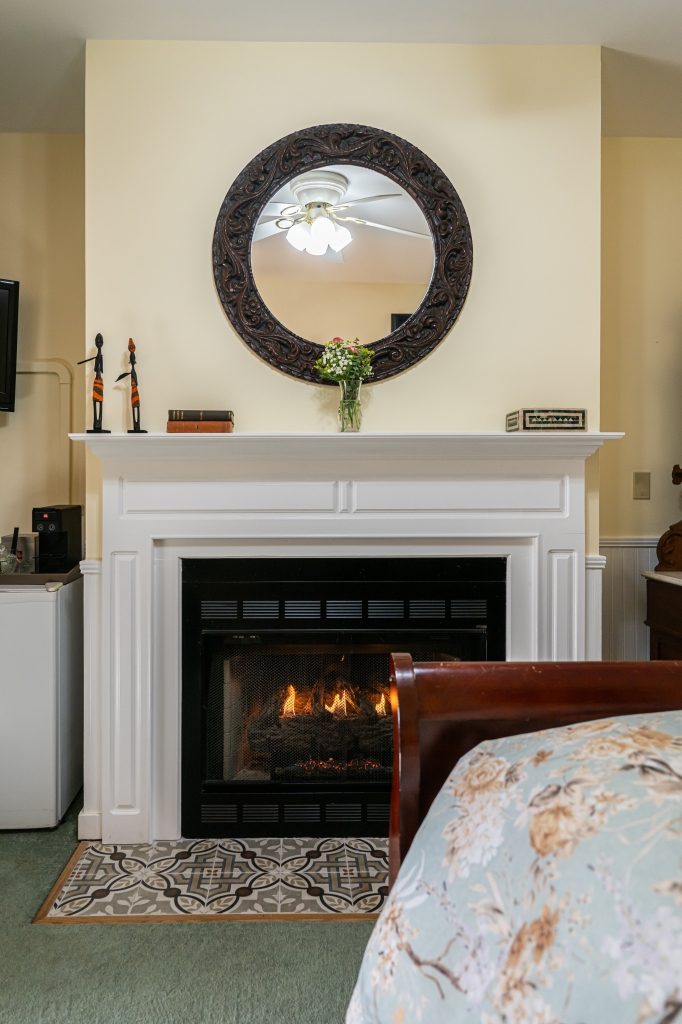 Elephant Walk suite — fireplace mantel with carved wood mirror at The Reynolds Mansion Carriage House