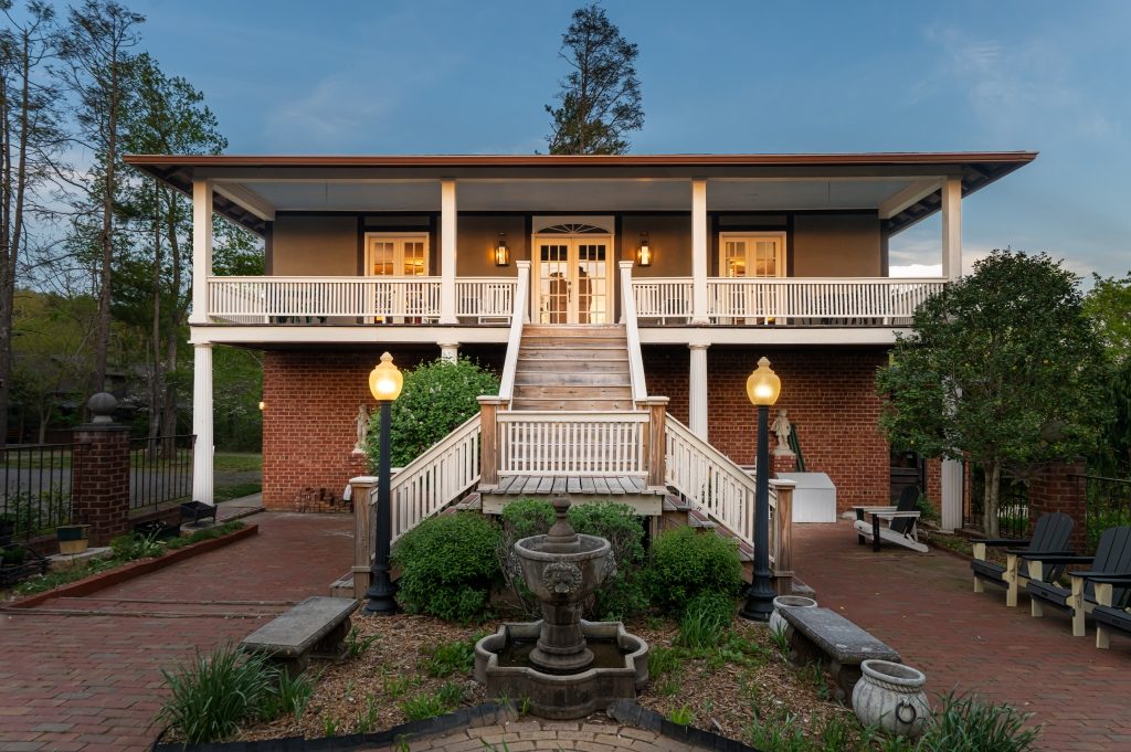 The Carriage House at twilight — full architectural view with covered porch and lit windows at The Reynolds Mansion, Asheville