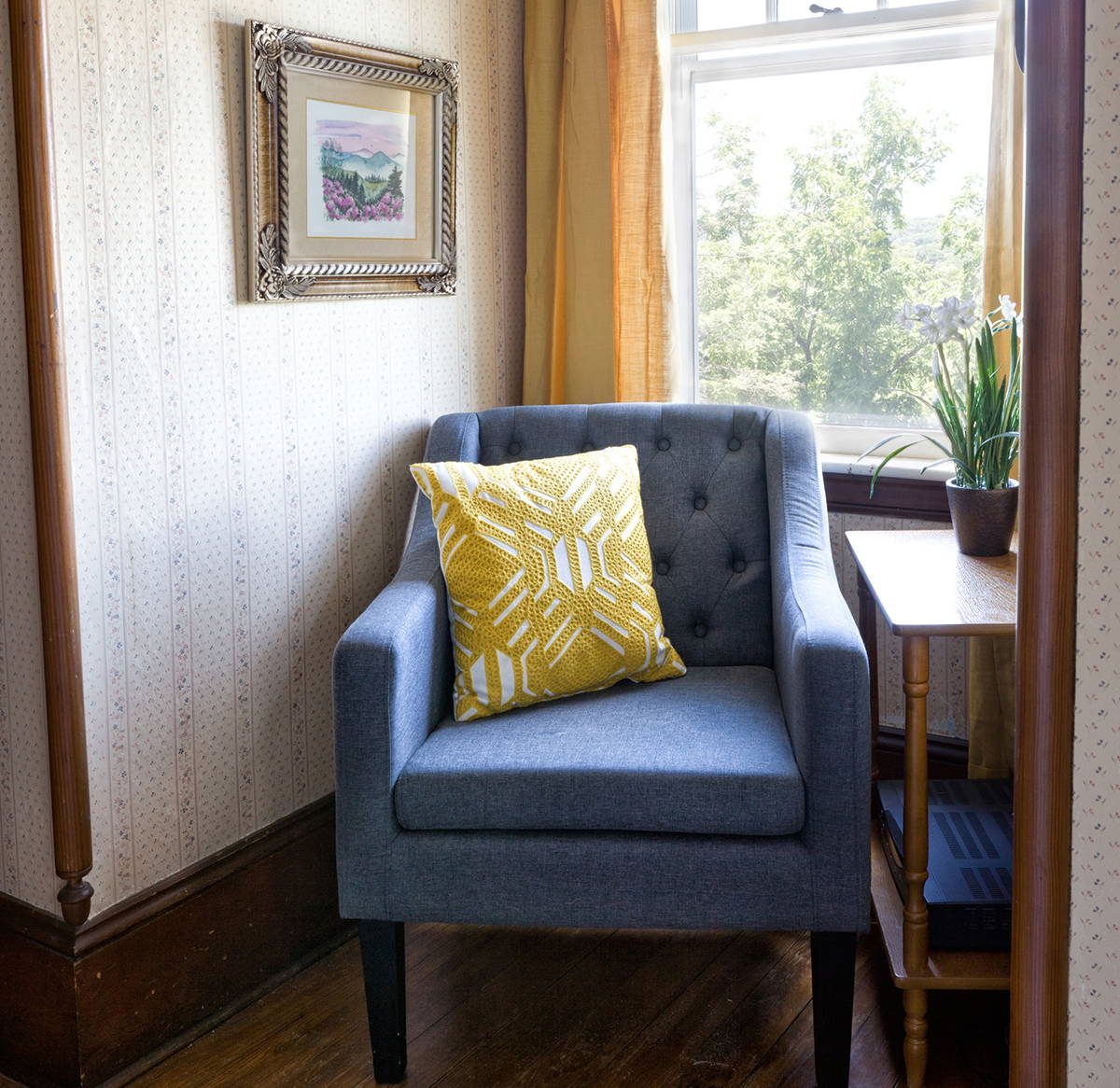 Inez room — third-floor sitting corner with armchair by window and view of trees at The Reynolds Mansion