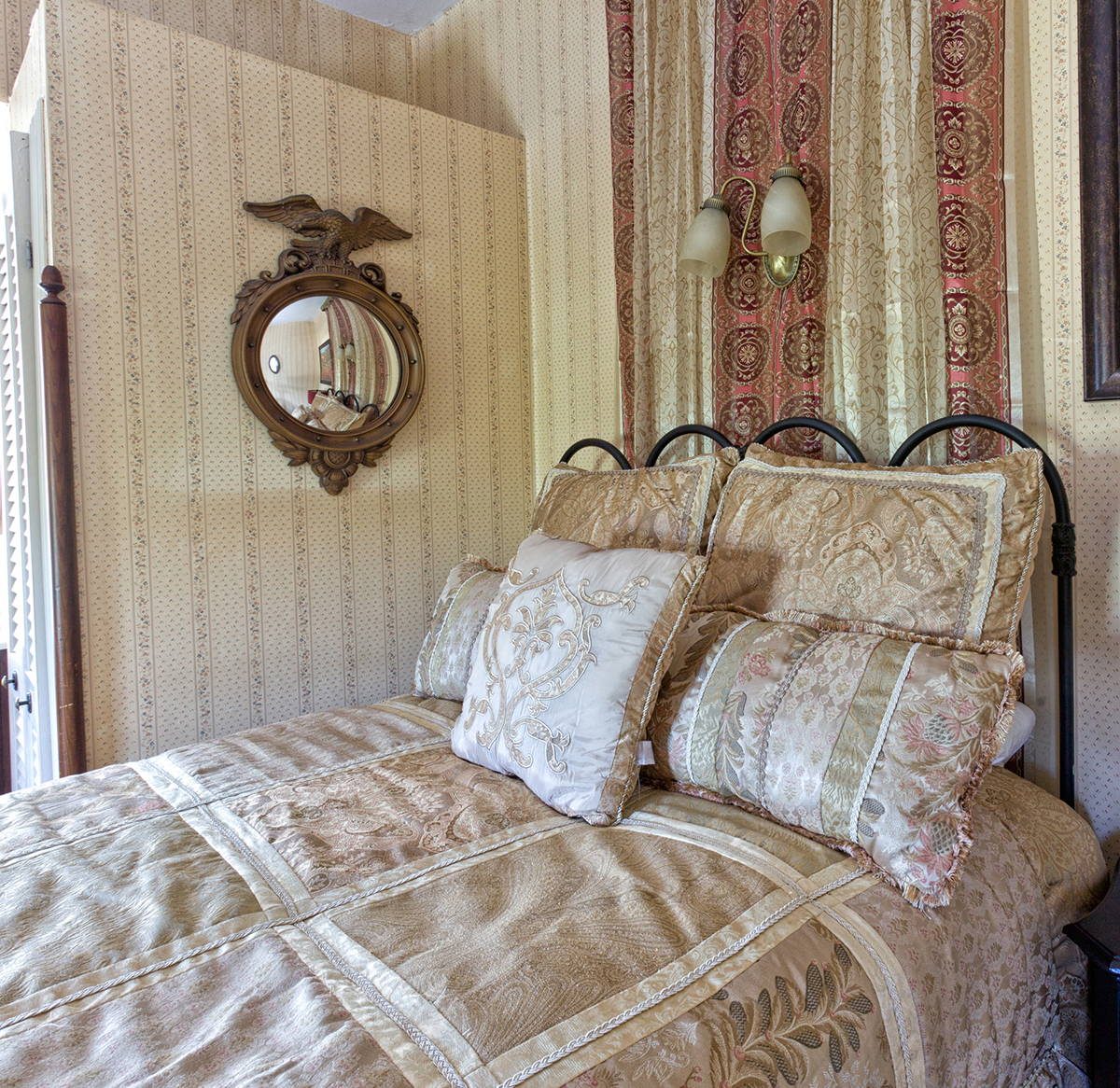 Inez room — full bed with iron frame and cream linens against floral wallpaper at The Reynolds Mansion