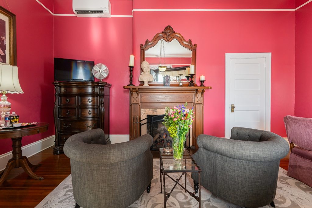 Claudette room sitting area — gray armchairs, gas fireplace with marble mantel and bust at The Reynolds Mansion