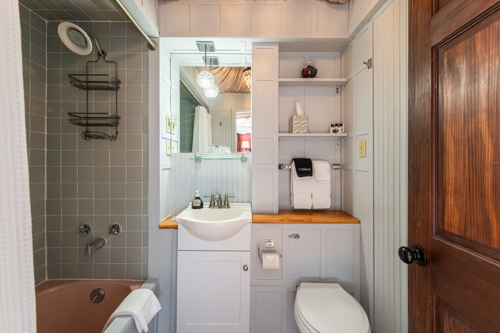 Claudette room private bathroom — soaking tub with shower, vanity, and beadboard wainscoting at The Reynolds Mansion