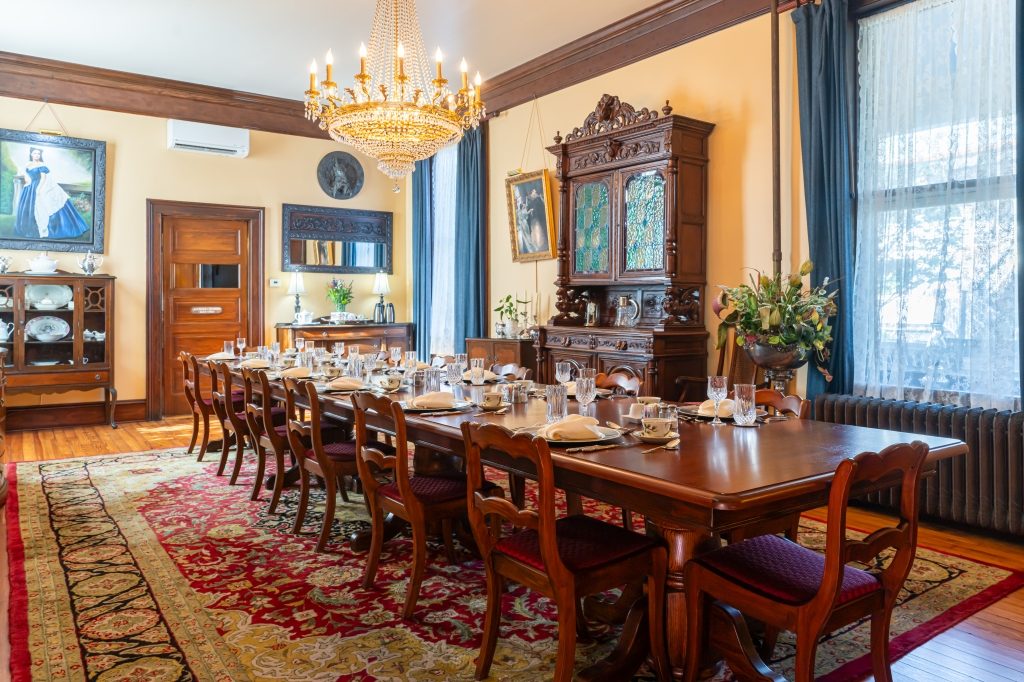 Antique mahogany dining table set under a crystal chandelier in the dining room at The Reynolds Mansion