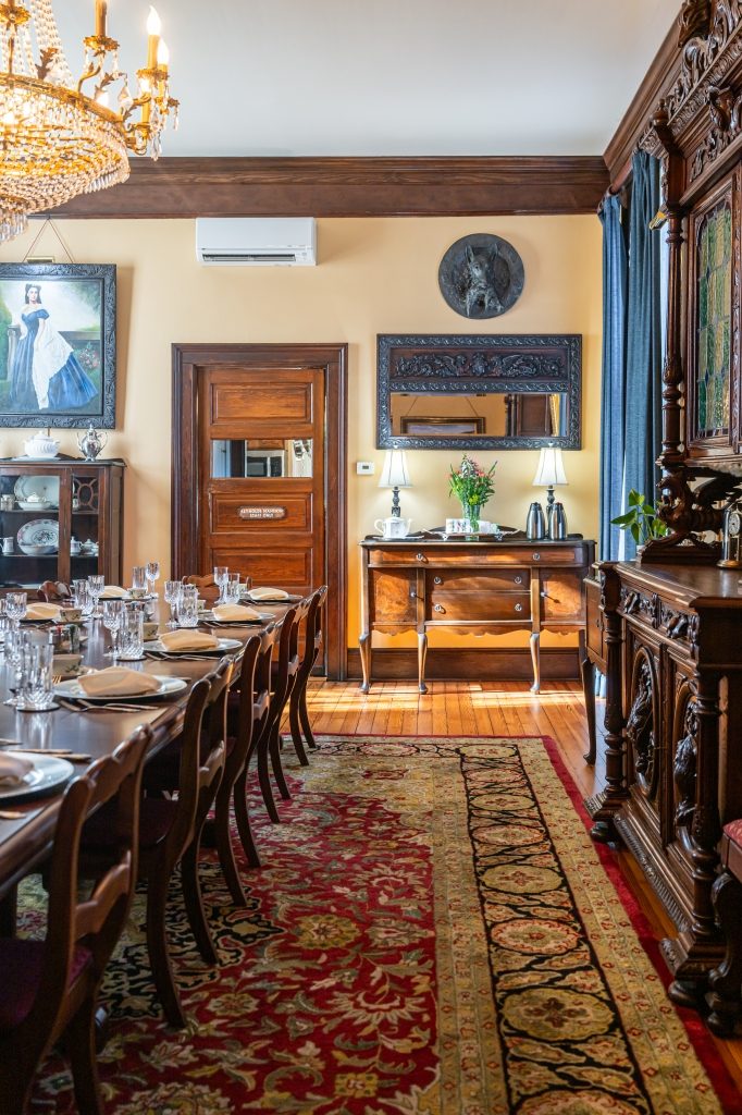 Formal dining room at The Reynolds Mansion set with crystal chandelier, antique buffet, and table prepared for the four-course breakfast