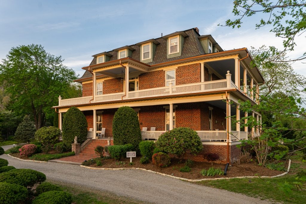 The Reynolds Residence at The Reynolds Mansion — an 1847 brick mansion with mansard roof, double-decker wraparound porches, and historic landscaping in Asheville, NC