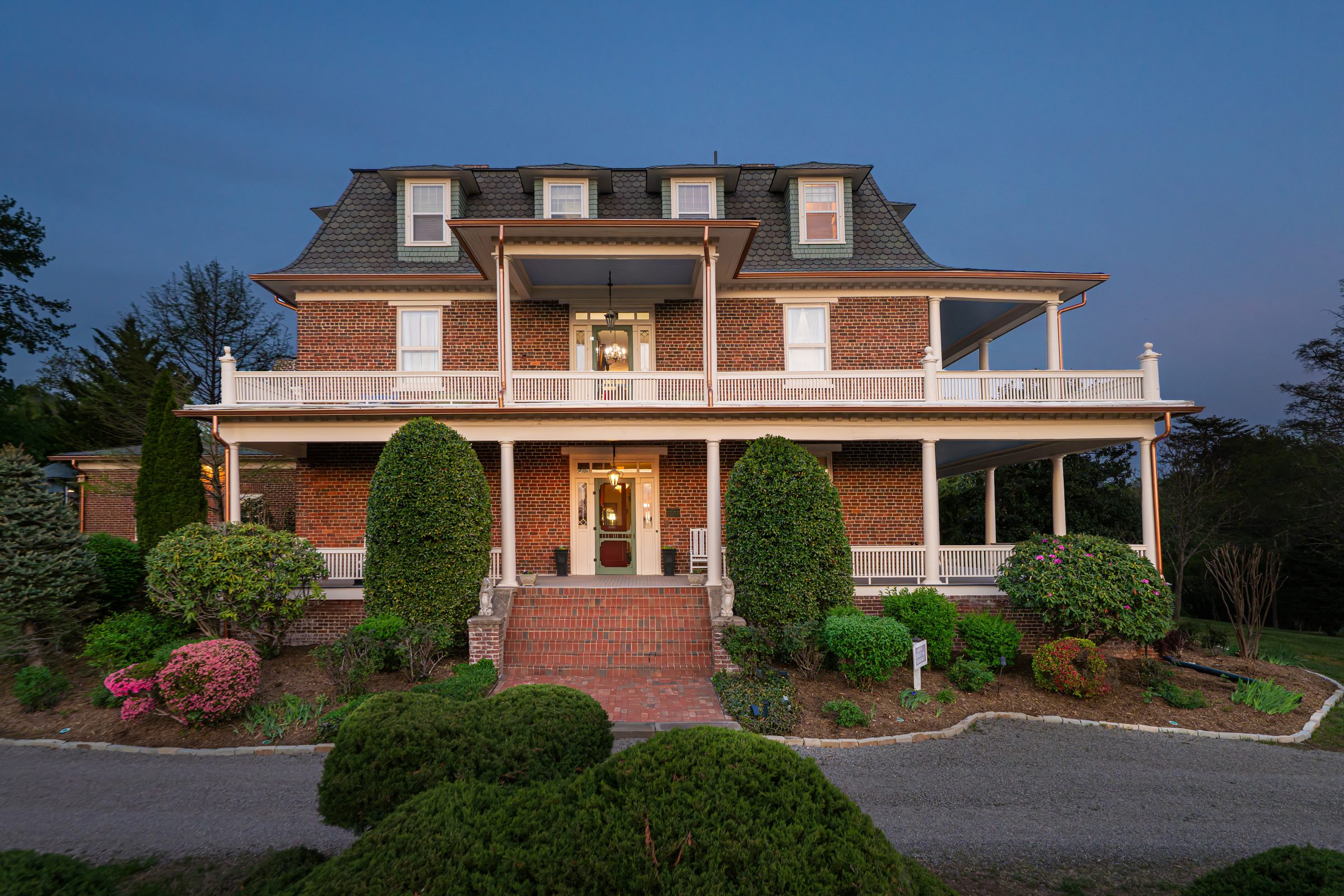 The Reynolds Mansion's brick façade with the wraparound porch and Blue Ridge Mountains in the background