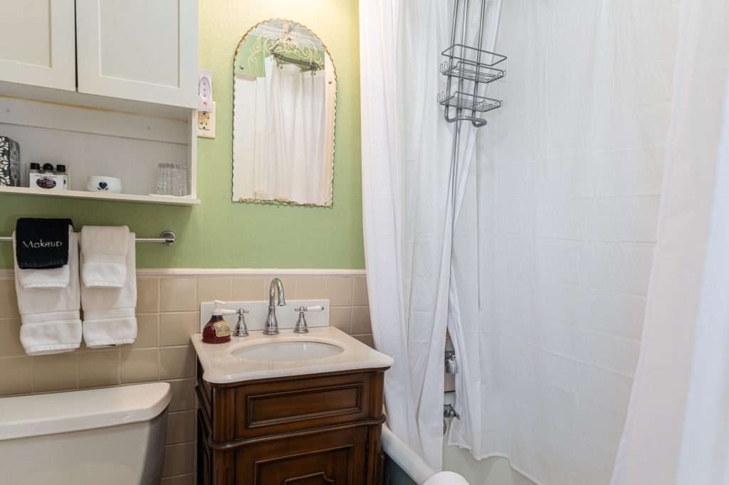 Glenda room private bathroom — vanity with shower and white towels at The Reynolds Mansion