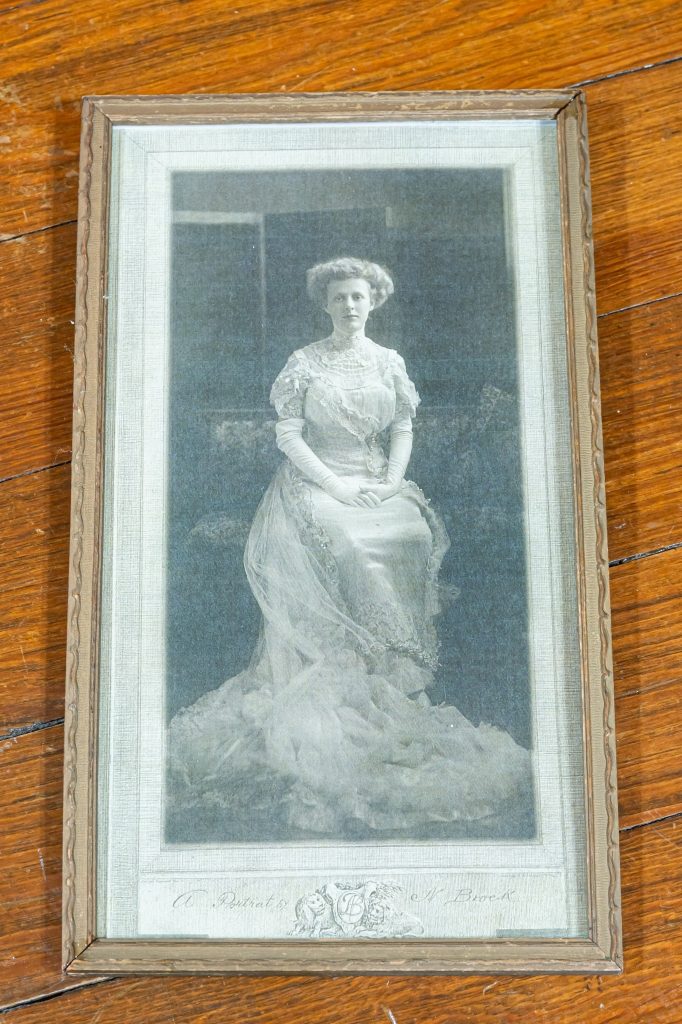A formal Reynolds family portrait displayed at The Reynolds Mansion — a young woman in a long lace gown, early 1900s
