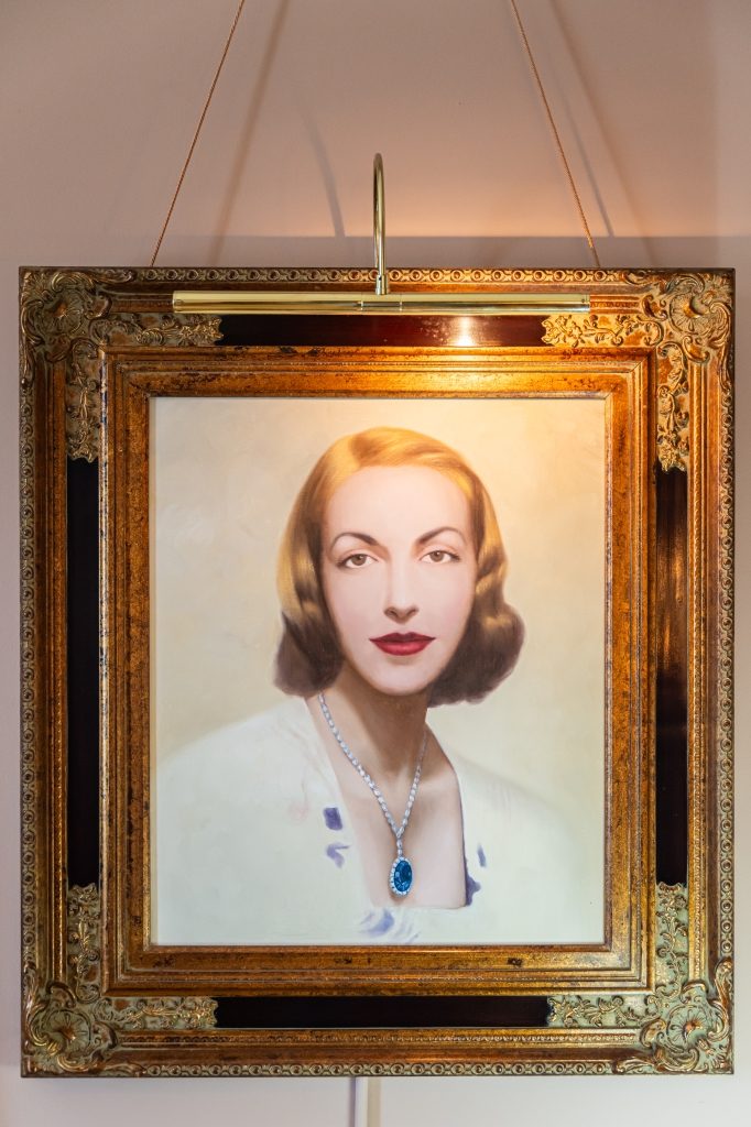 Oil portrait of a woman wearing a blue gem pendant, displayed at The Reynolds Mansion