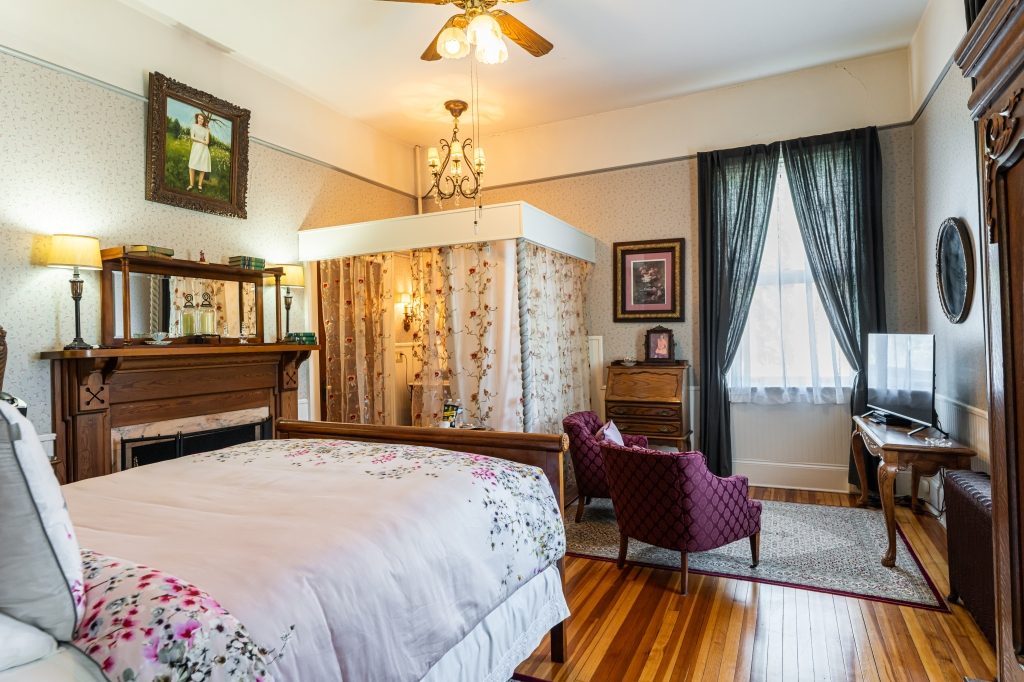 Katie room — queen sleigh bed with floral bedspread, paisley wallpaper, gas fireplace and antique secretary at The Reynolds Mansion