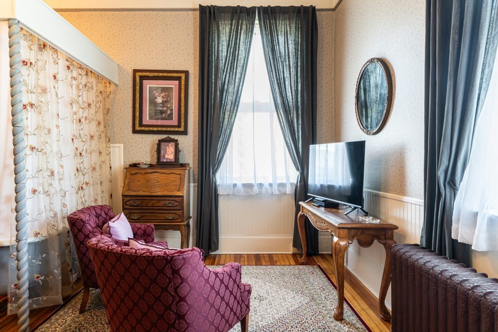 Katie room sitting area — paisley armchair, antique secretary desk, mirror at The Reynolds Mansion