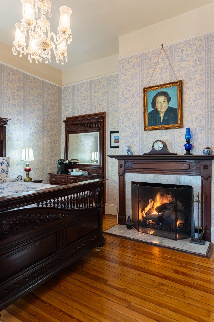 Lila room fireplace — working gas fireplace with ornate marble mantel and period portrait at The Reynolds Mansion