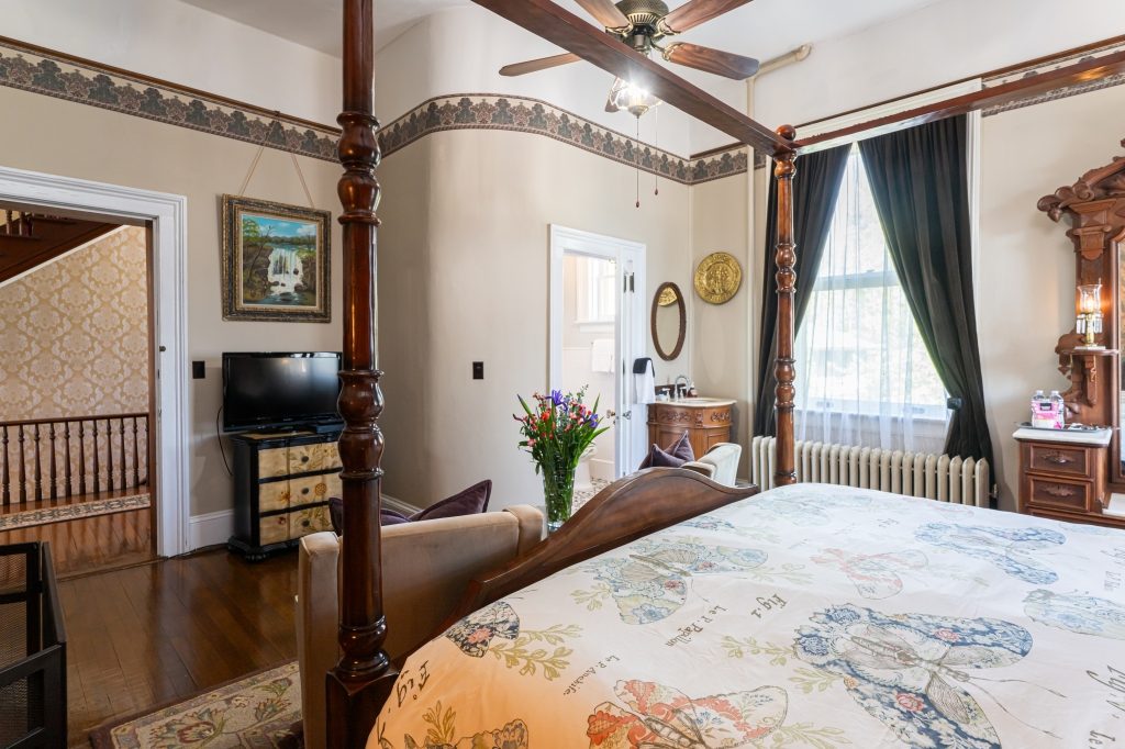 Linda room — alternate view showing canopy bed, dresser, and TV at The Reynolds Mansion