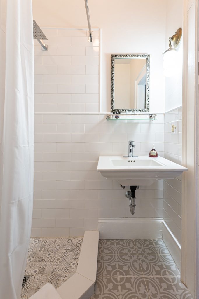Maggie room private bathroom — pedestal sink with white subway tile and decorative tile floor at The Reynolds Mansion