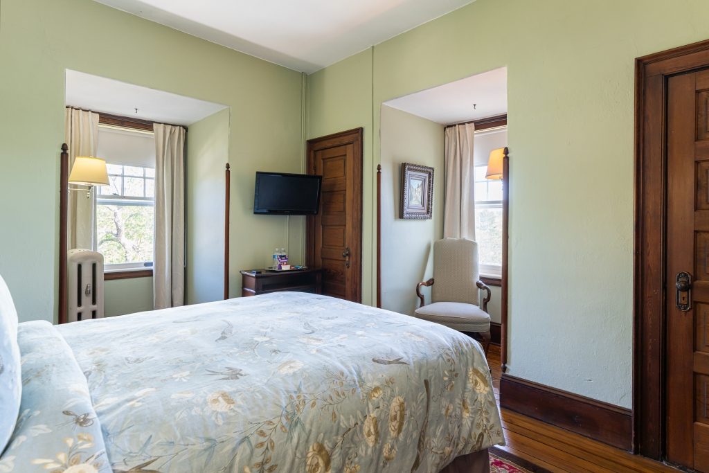Vera room — wider view showing bed, TV, and two windows at The Reynolds Mansion