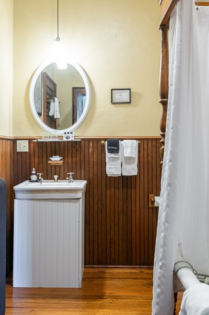 Vera room private bathroom — pedestal sink with beadboard wainscoting and decorative tile floor at The Reynolds Mansion