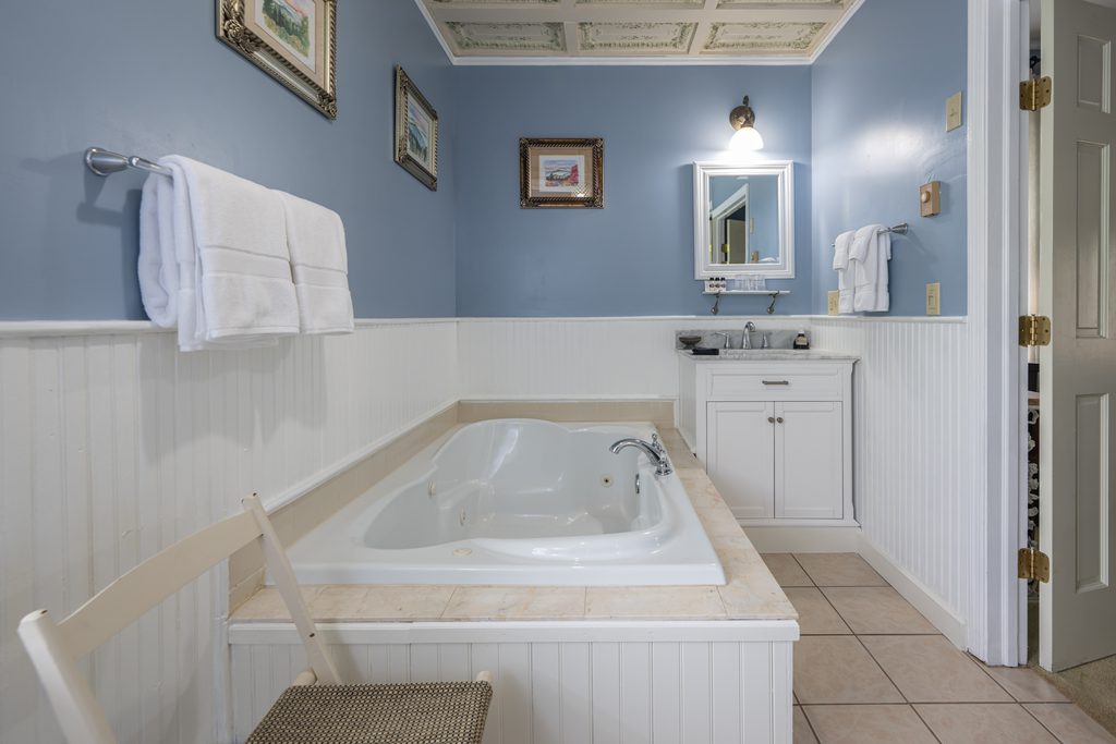 Blue Hydrangea suite — Jacuzzi tub under framed artwork in the blue-and-white bathroom at The Reynolds Mansion