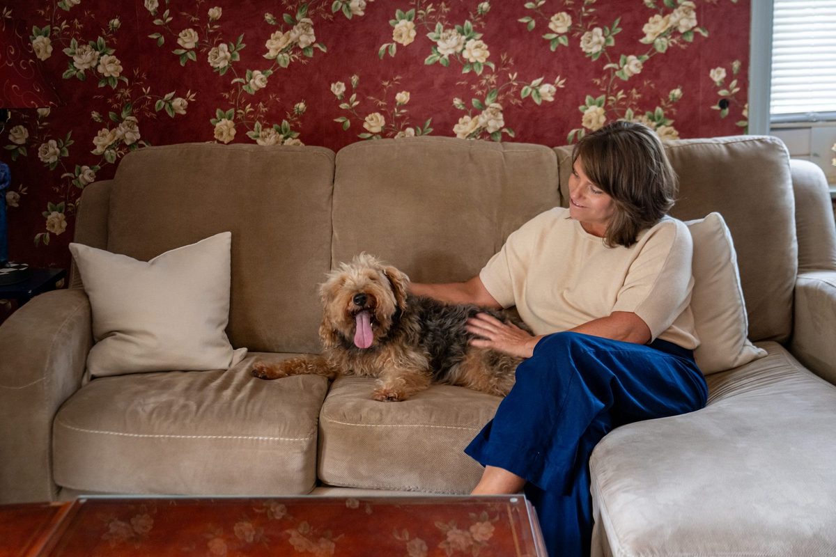 A guest and her small dog relaxing on the sofa in a Carriage House suite at The Reynolds Mansion