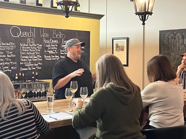 Quench Wine Bistro bar — guests enjoying wine while the bartender pours from an extensive selection in Reynolds Village