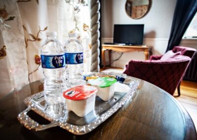 A living room scene with two water bottles and yogurt cups on a silver tray on a wooden table.