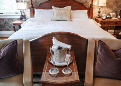 Elegant bedroom with a plush bed, patterned wallpaper, and a bedside table with a vintage teapot set.