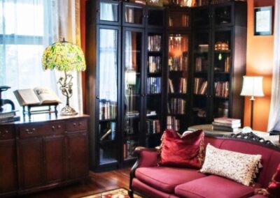 Elegant living room with red sofa, wooden furniture, and a filled bookcase.