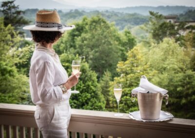 A woman standing on a balcony holding a glass of wine.