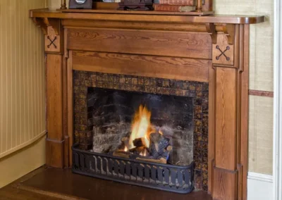 A Fireplace with a burning fire, surrounded by ornate wooden mantle and vintage decorations.