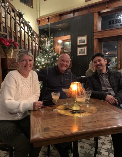 Three people smiling at a table with a lit candle in a cozy restaurant setting.